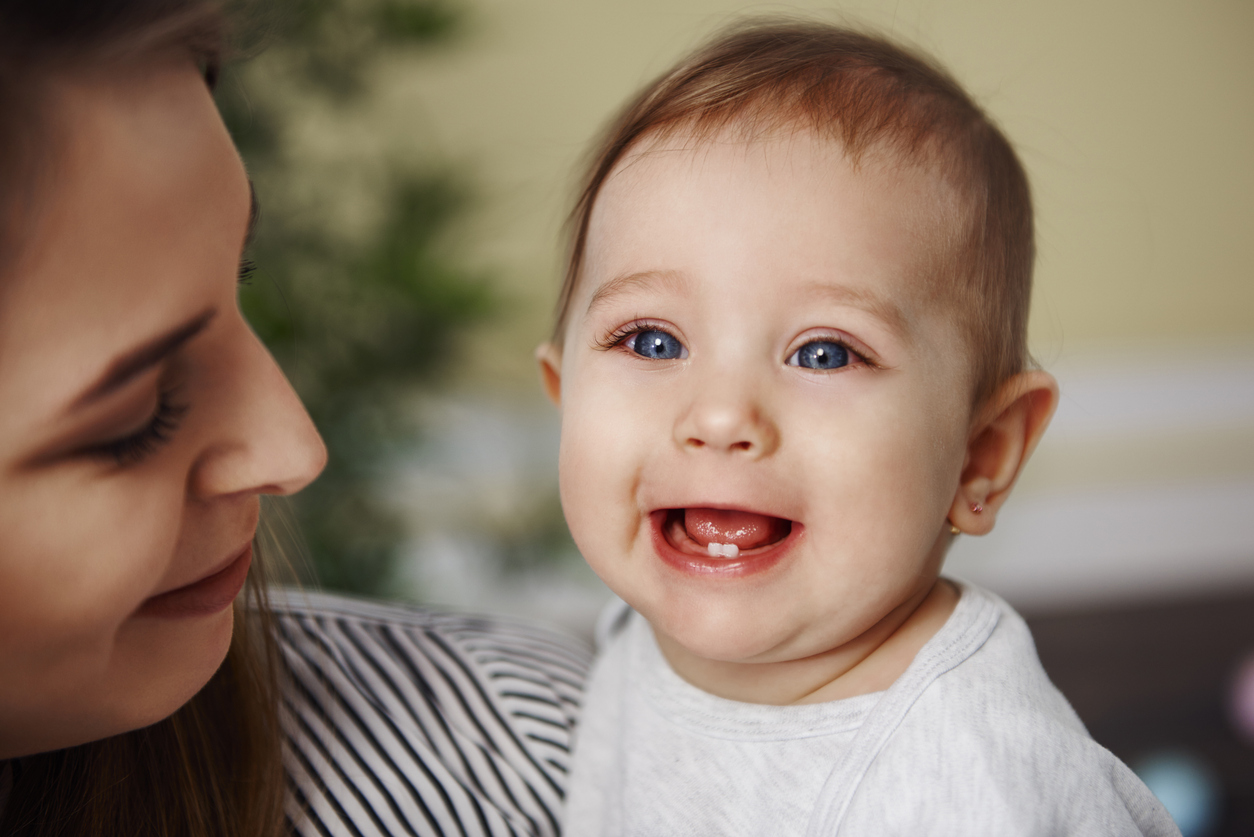 mamá mira los primeros dientes de bebé